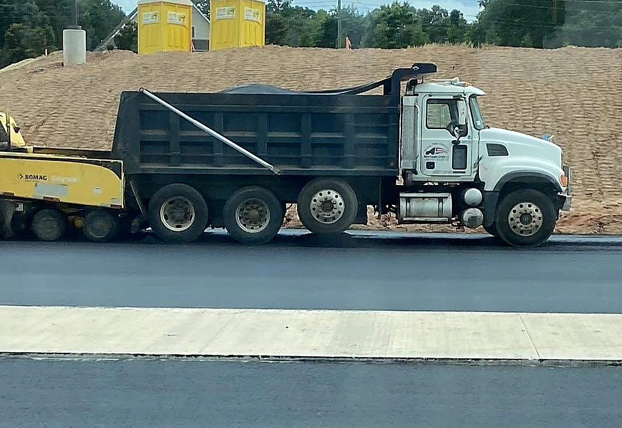 Dump truck and paving equipment working together on a project
