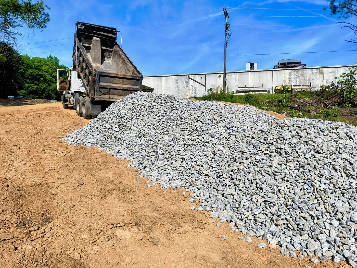 Dump truck delivering a large pile of aggregate on site