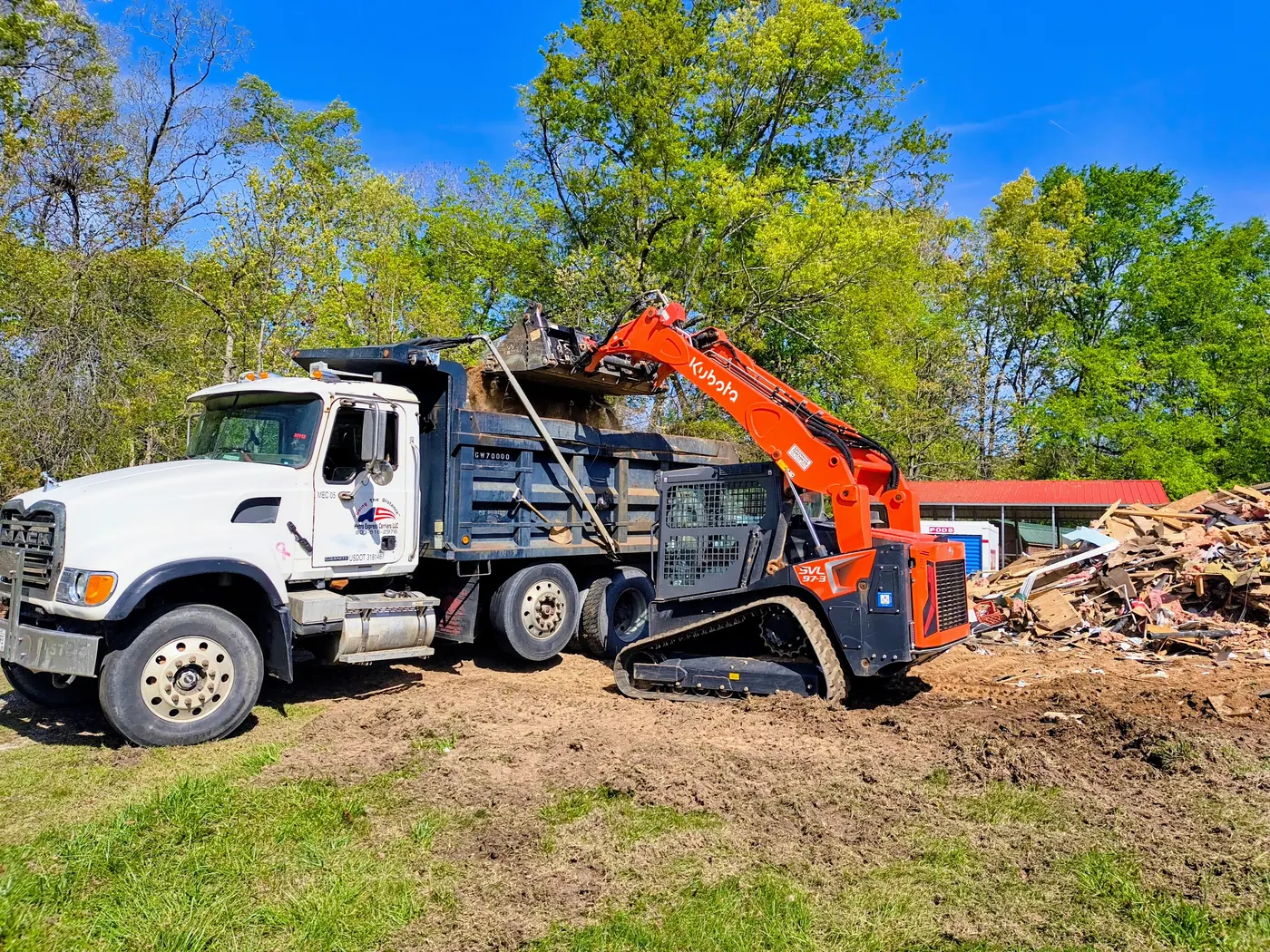 Dump truck and compact loader clearing debris from a work site